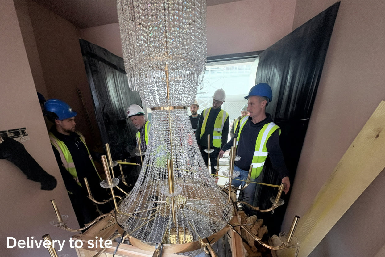 Large crystal chandelier being installed with workers in the background.