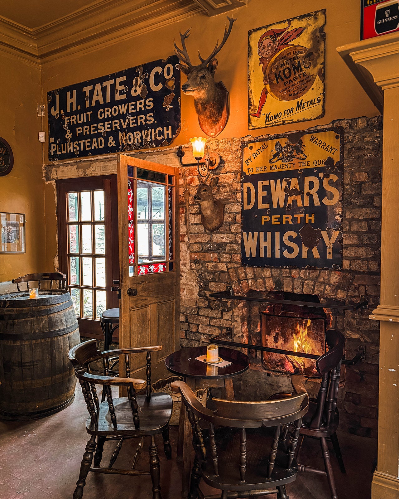 Vintage-style bar with rustic decor, including a fireplace, wooden furniture, and antique signs.